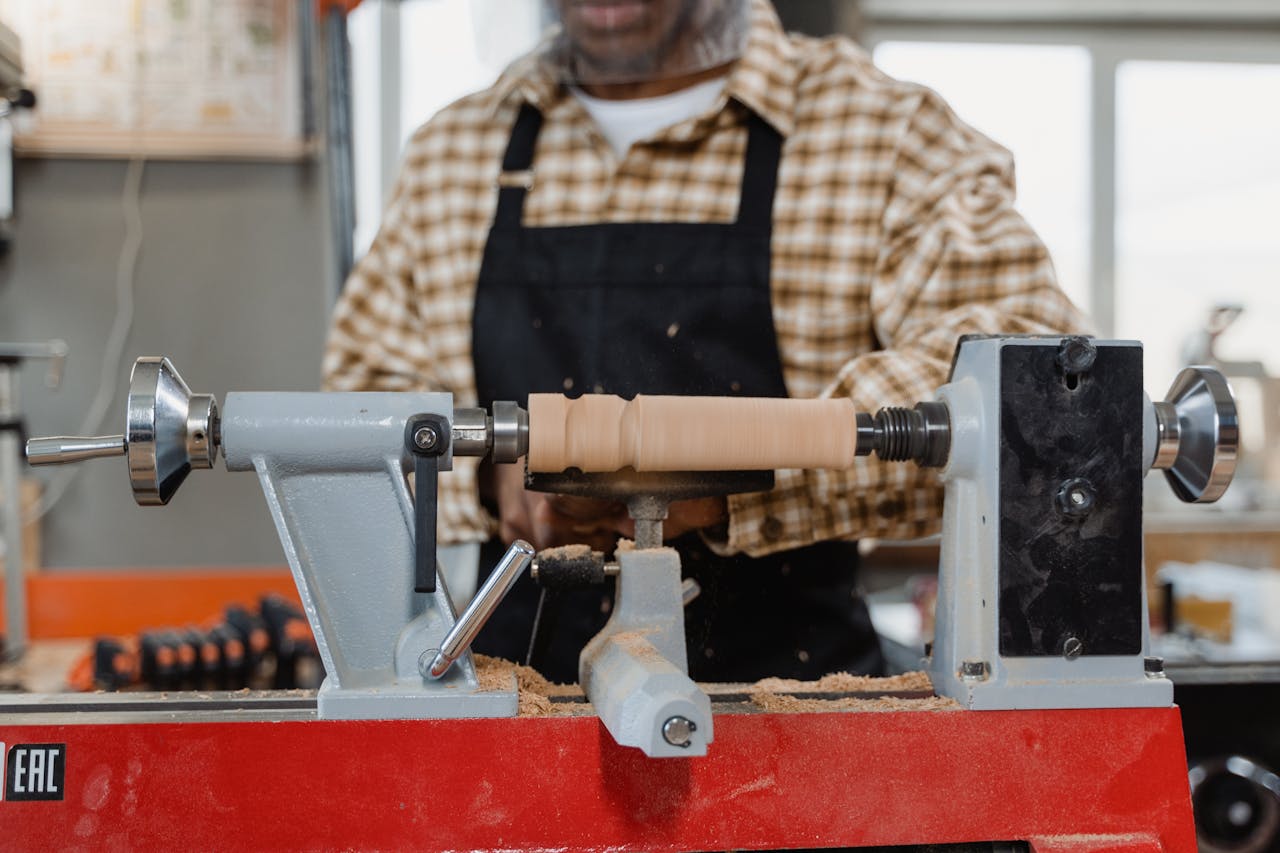 why-choose-us Close-up of a craftsman using a lathe in a workshop, showcasing woodworking skills.